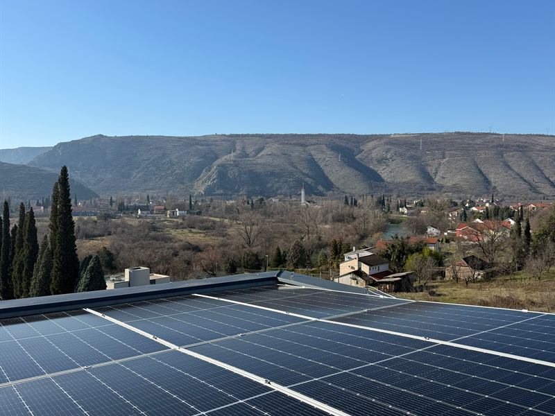 Solarni paneli na ravnom krovu sa planinama u pozadini